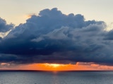 Ocean sunrise under dark cumulus clouds.